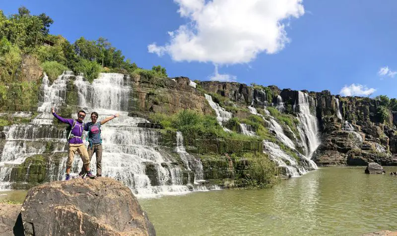 Justin Huynh and Jackie Szeto, Life Of Doing, pose in front of the Pongour Waterfall, Vietnam
