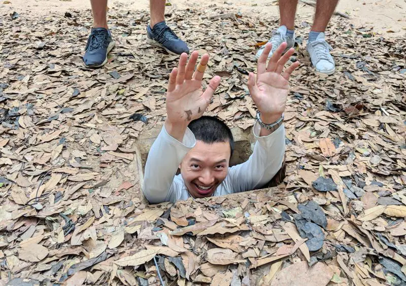 Justin Huynh, Life Of Doing, has his hands up while going down one of the holes in Cu Chi Tunnels, Vietnam.