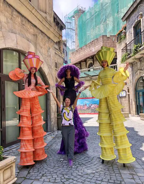 Three women with long legs posing with Jackie. The women are walking on stilts.