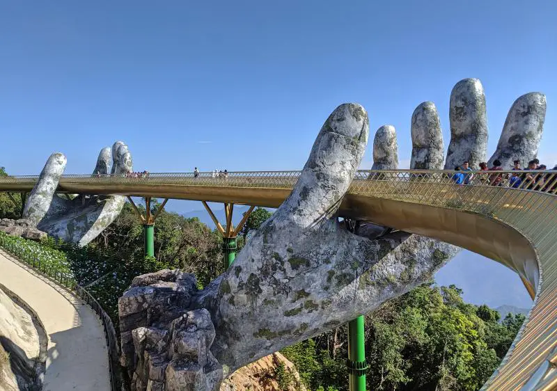 Two stone hands holding up a golden bridge at the Sun World Ba Na Hill Theme Park in Danang, Vietnam