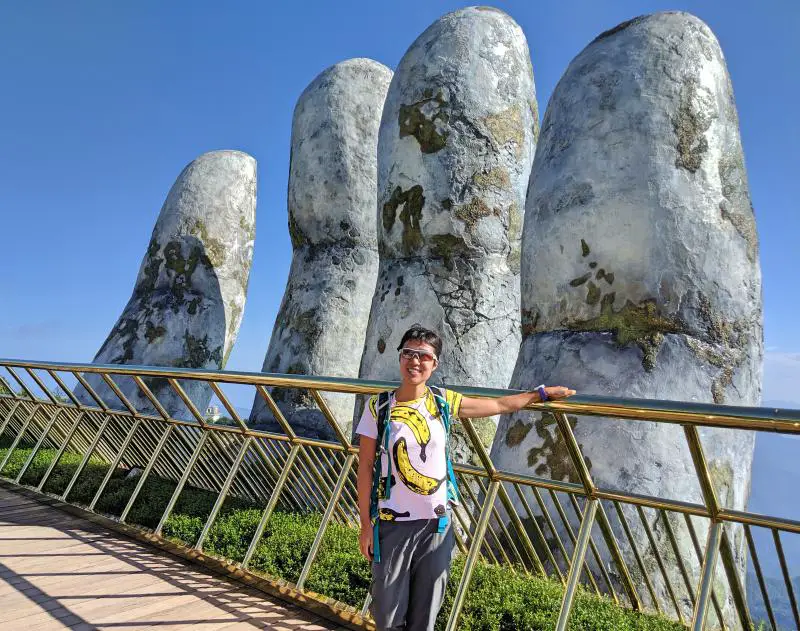 Standing next to one of the giant stone hands at the famous Golden Bridge at Sun World Ba Na Hills in Danang, Vietnam.