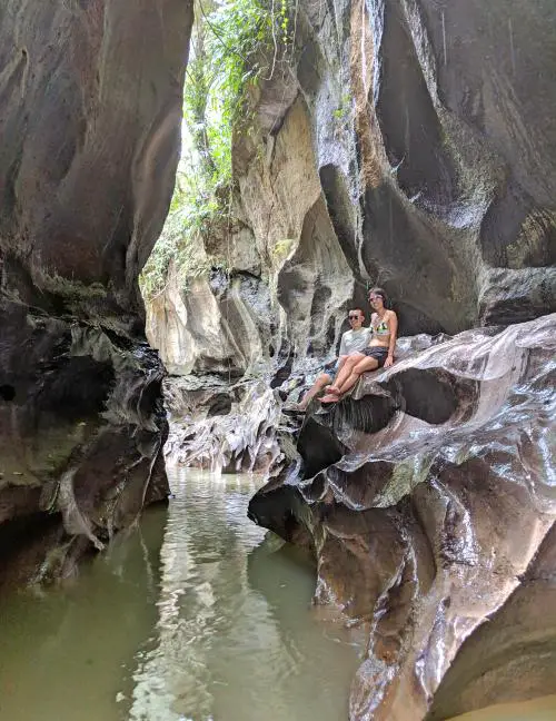 Justin Huynh and Jackie Szeto, Life Of Doing, sit on the edge of the natural rock formations at Hidden Canyon in Bali.