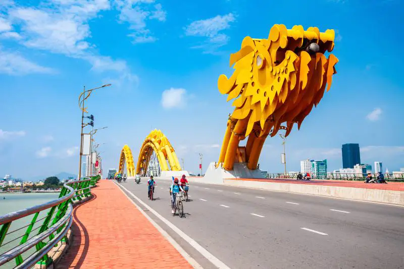 View of the golden Dragon Bridge and motorcyclists in Danang, Vietnam