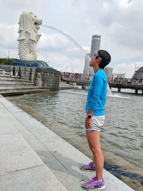 A woman posing with the merlion statue at Merlion Park in Singapore's Marina Bay area.