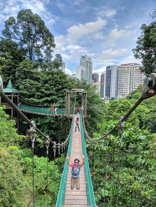  Jackie Szeto, de Life Of Doing, saute sur le pont suspendu du parc écologique KL Forest. C'est un endroit amusant pour visiter les ponts suspendus auvent.