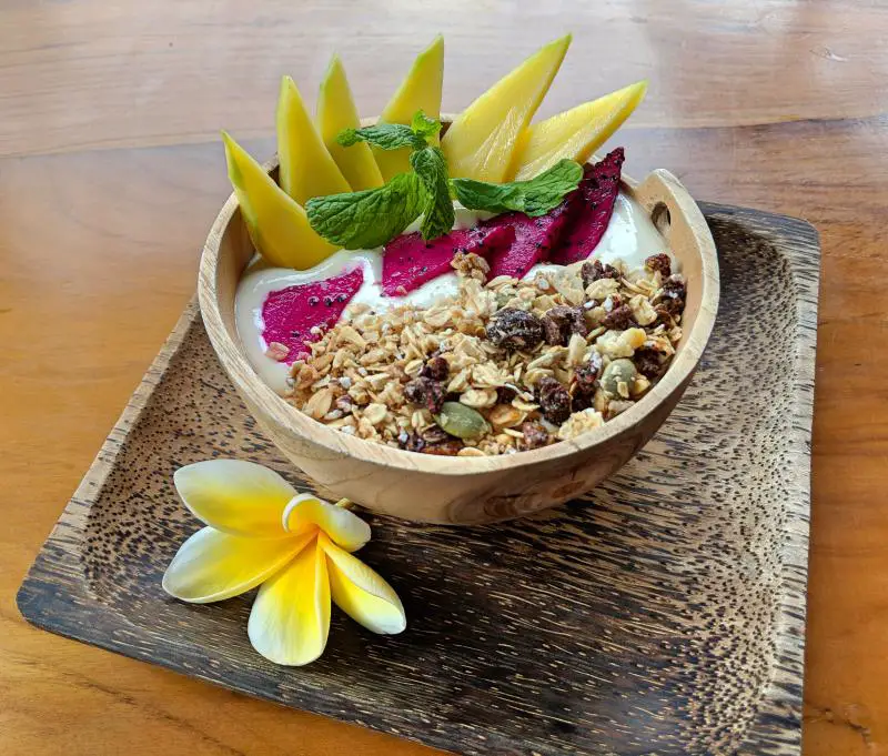 Healthy and fresh bowl with granola, yogurt, dragon fruit, and mango slices at Tropical Juice Corner.