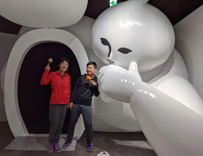Jackie Szeto and Justin Huynh of Life Of Doing poses with an inflatable Unberto, the mascot of the Unko Museum.
