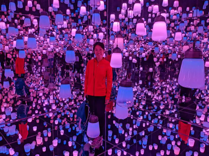 Jackie from Life Of Doing is in the teamLab Borderless's Forest of Resonating Lamps which has purple and pink lights.