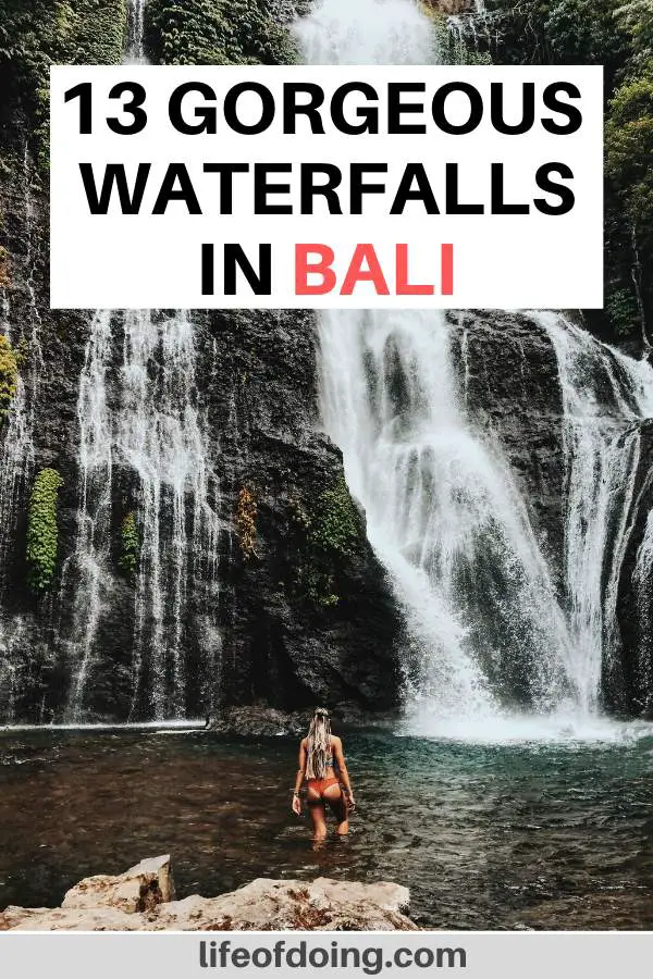 A woman in a swimsuit wades in one of the Bali waterfalls.