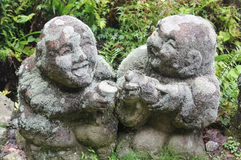 Two little stone men covered in moss and enjoying a drink at Otagi Nenbutsu-ji in Kyoto, Japan. It's a top place to visit during your 5 days in Kyoto.