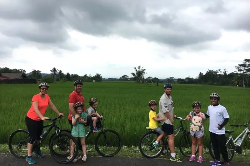 A family rides stops along a rice paddy field during their bike ride through Ubud