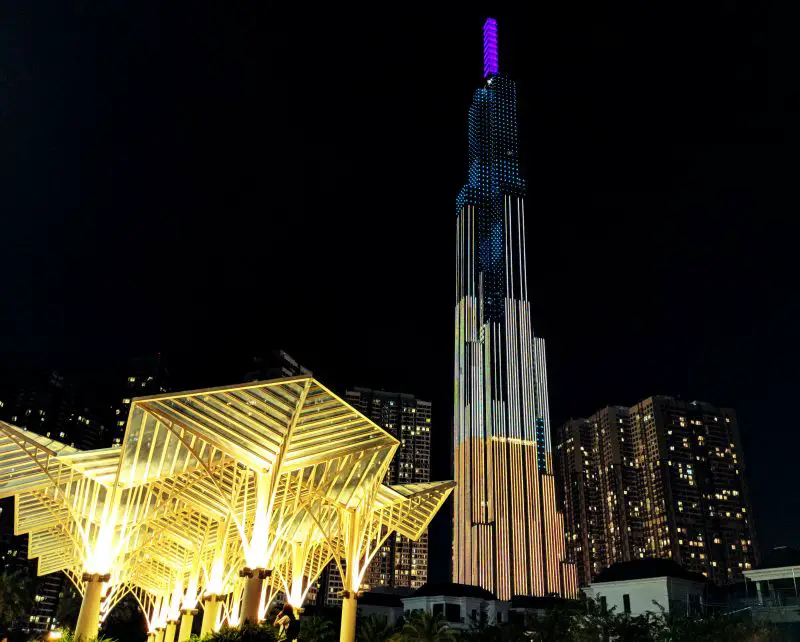 A tall skyscraper building that is 81 stories high (called Landmark 81) illuminating lights of purple, yellow, and white colors at night in Ho Chi MInh City, Vietnam