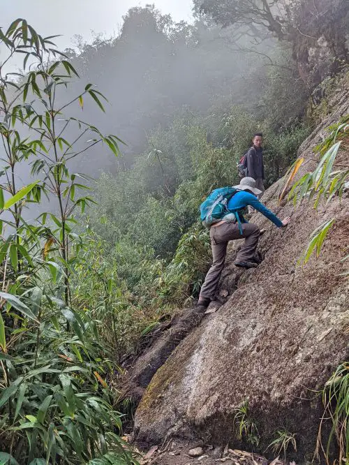 Jackie Szeto, Life Of Doing, and guide climb up a slanted rock on the way to Fansipan summit in Vietnam