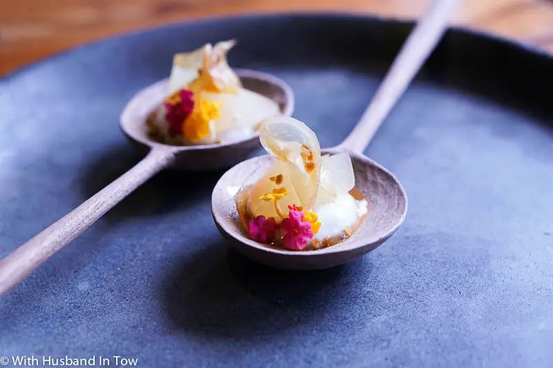 Two dumplings with edible flowers on wooden spoons