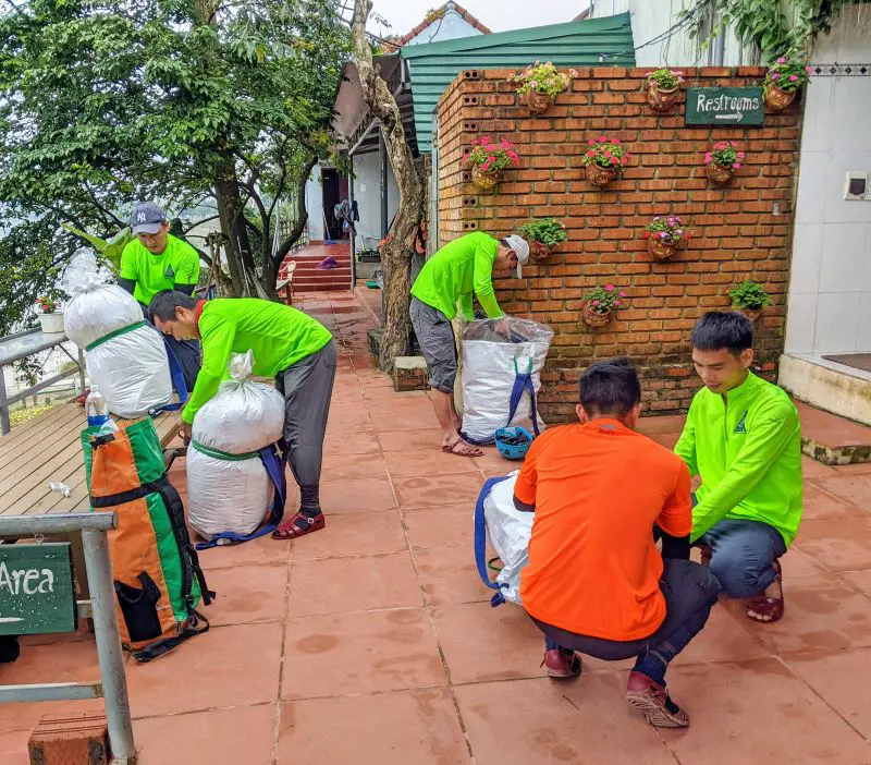 Five porters pack supplies and gear into their backpacks to bring on the Hang En trek