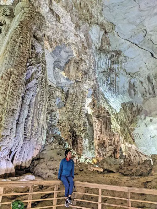 Jackie Szeto, Life Of Doing, sit on the rail with the stalactites and stalagmites in Phong Nha Cave in Phong Nha Ke Bang National Park