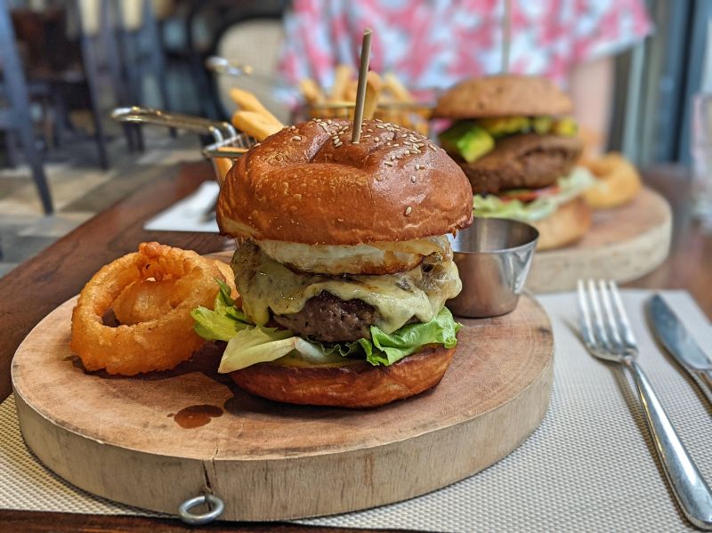 Chef's burger with fried egg, lettuce, cheese, fried onion rings, and french fries at Cafe Tartine in Ho Chi Minh City