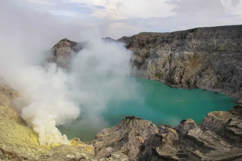 Steam from a turquoise volcanic lake crater at Ijen, Indonesia