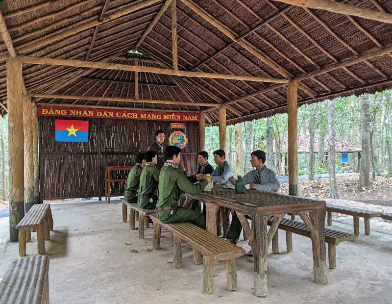 Replica of 7 soldiers and 1 leader of the Vietnamese army having a discussion under a straw covered hut in Ma Da's Southeast Commissioners Area Ruins.