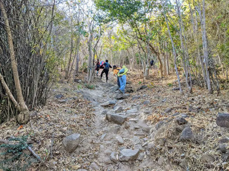 Four hikers walking up the rocks of the Nui Lon hiking trail in Vung Tau, Vietnam