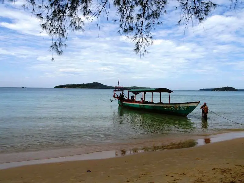 A green, red, and white boat in the middle of the ocean in Sihanoukville, Cambodia
