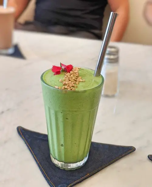 Avocado smoothie with small nuts and a metal straw