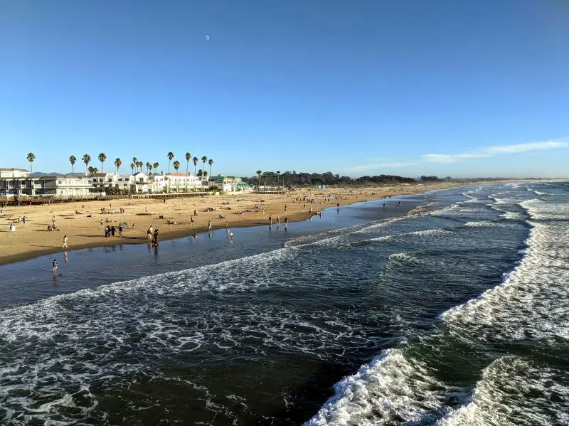 Visitors relaxing on the golden beaches of Pismo Beach and walking in the ocean water.
