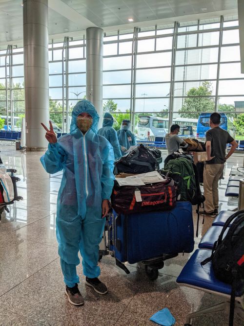 Jackie Szeto, Life Of Doing, wearing a blue PPE outfit after collecting check in luggage.