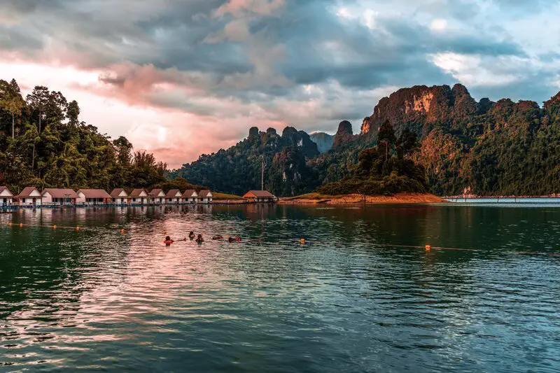 A group of people swimming in a lake at sunset at Khao Sok National Park, Thailand