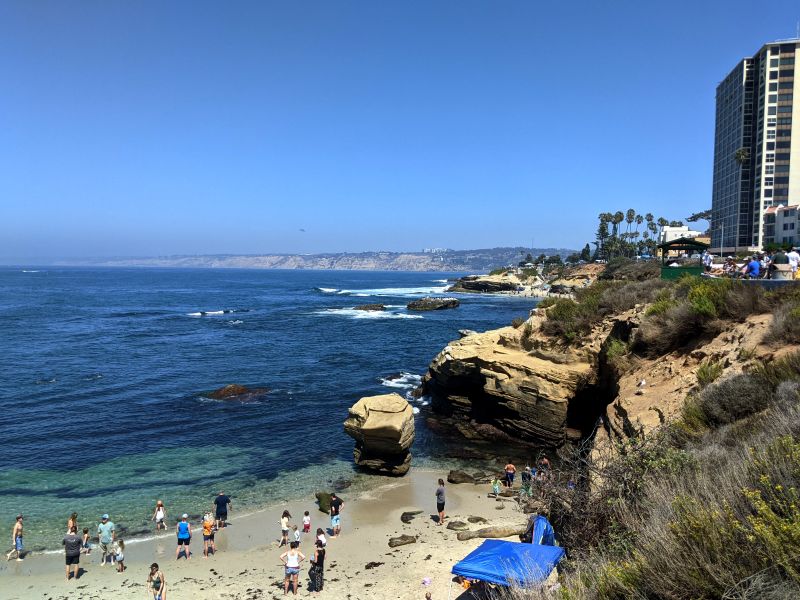 Groups of people standing on the white sandy beach in La Jolla, San Diego, California