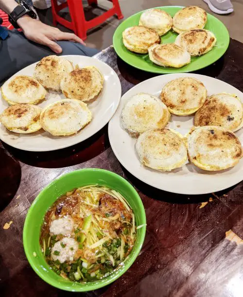 Three plates of five rice cakes and dipping sauce at Bánh Căn Nhà Chung in Dalat, Vietnam
