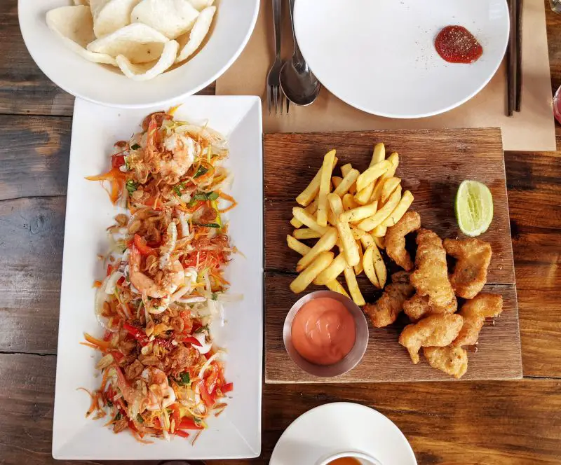 One plate of seafood and shrimp salad with shrimp chips and another plate of fried fish and french fries at Barn House in Dalat, Vietnam