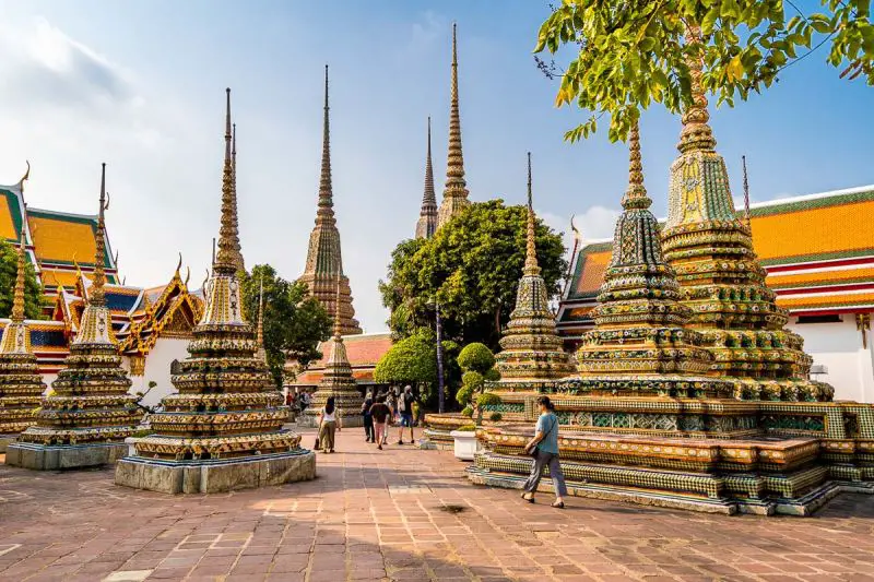 People passing through a Buddha temple complex called Wat Pho in Bangkok Thailand