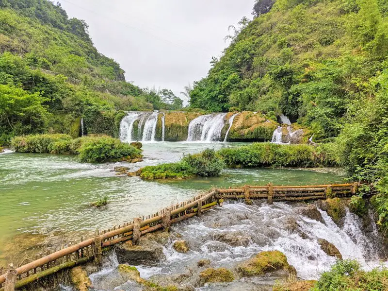 A smaller waterfall, Co La Waterfall, is surrounded by trees in Cao Bang, Vietnam