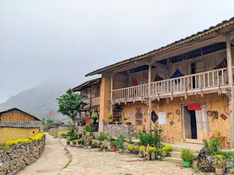 A beige two story house with plants and a fence made out bricks in the Lo Lo Chai Village, Ha Giang, Vietnam