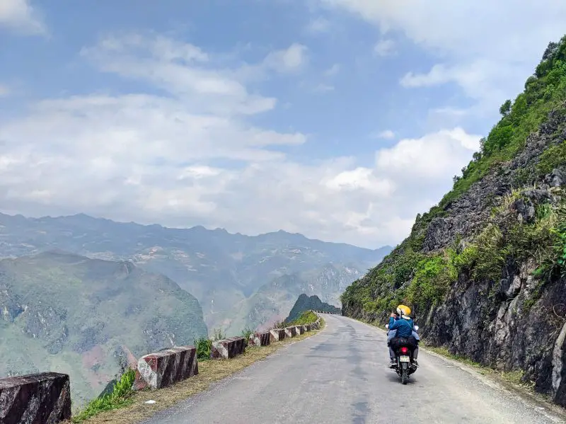 Two people on a motorbike riding along Ma Pi Leng Pass in Ha Giang, Vietnam