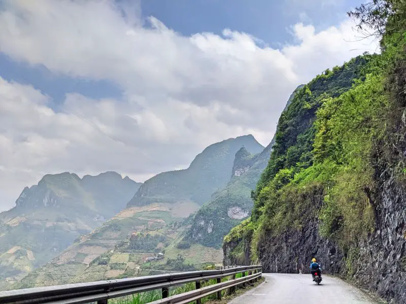 Two people on a motorbike riding along Ma Pi Leng Pass in Ha Giang, Vietnam