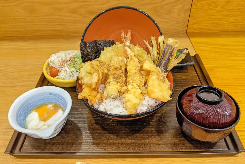A bowl of rice topped with tempura battered vegetables and seafood, salad, miso soup, and steamed egg at Quon, Ho Chi Minh City