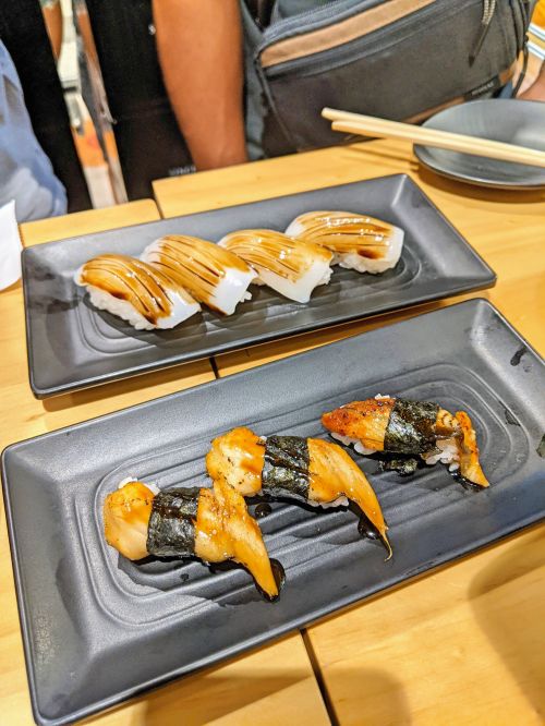 Two places of sushi. One plate has conger eel and grilled egg; second plate has squid sushi at Sushi Tiger, Ho Chi Minh City, Vietnam