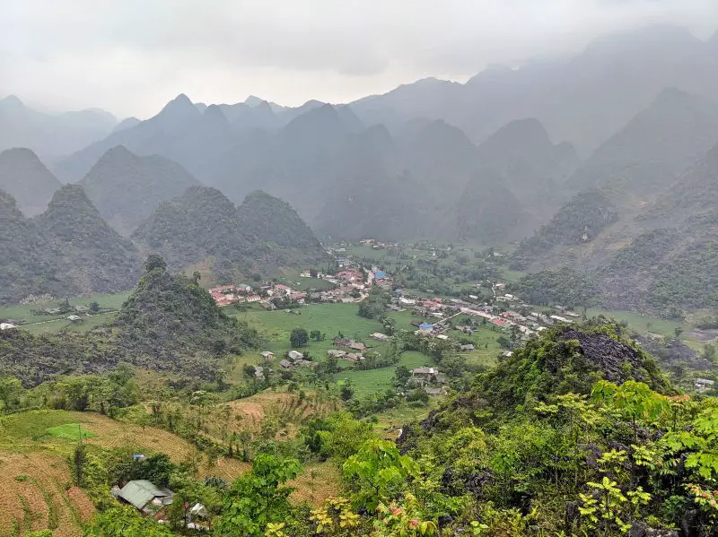 A small village with fields and tall mountains surrounding the area in Ha Giang, Vietnam