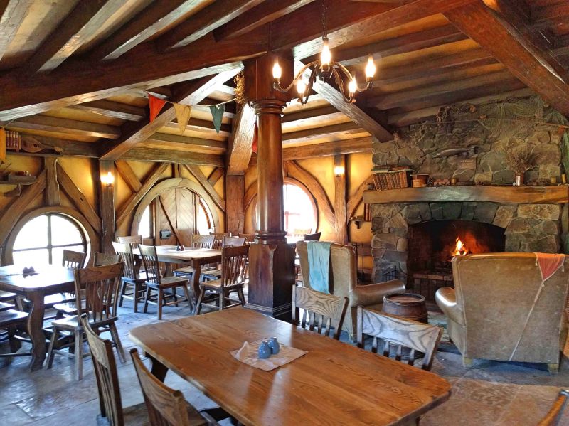 Tables, chairs, and a fireplace at the inside of the Green Dragon Inn, a part of Hobbiton Movie Set in Matamata, New Zealand