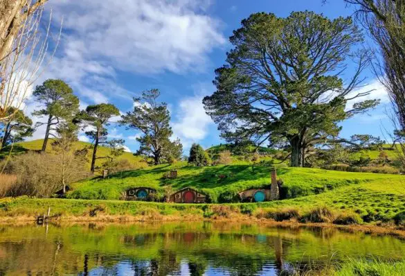 Lake view of the Hobbit holes and rolling green hills at Hobbiton Movie Set, Matamata, New Zealand