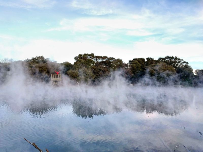 Jackie Szeto, Life Of Doing, stands on a wooden walkway with the steams from the geothermal springs coming up at Kuirau Park, Rotorua