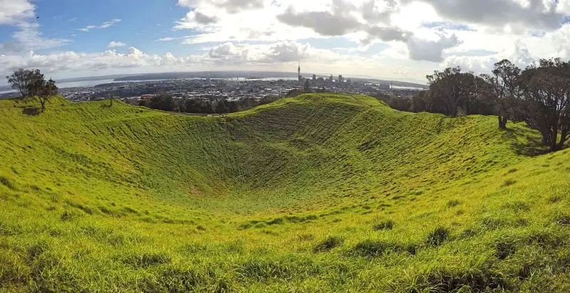 A crater on Mount Eden covered with grass and a view of the Auckland Central Business District in Auckland, New Zealand