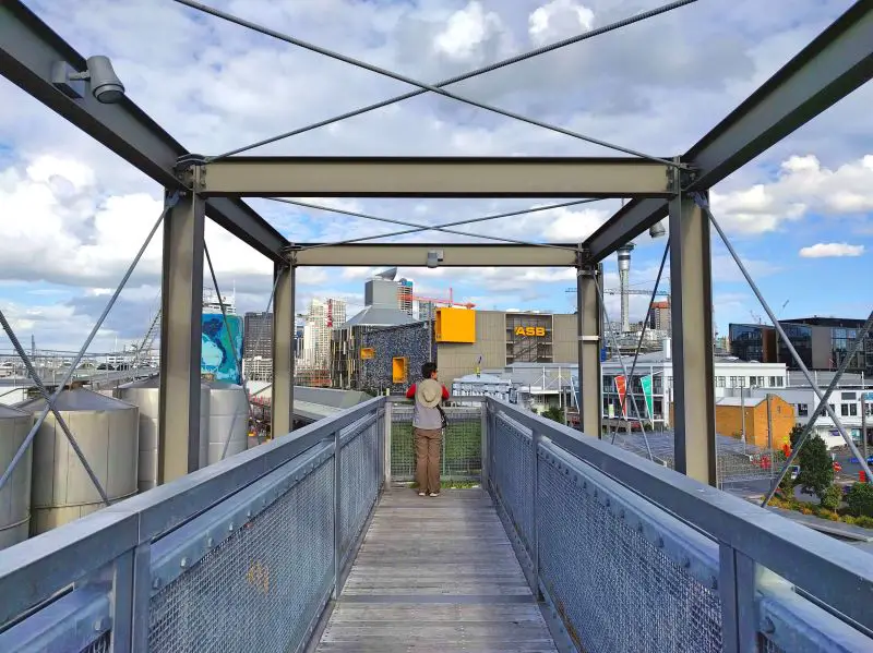 Jackie Szeto, Life Of Doing, stands at the end of the Silo Park bridge and overlooks the Wynyard Quarter and Auckland's Central Business District in New Zealand