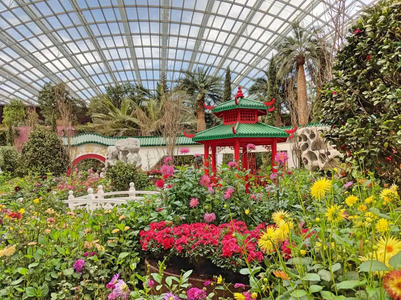 Singapore's Flower Dome has a Chinese pagoda area with pink, purple, and yellow flowers.