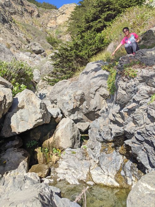 Jackie Szeto, Life Of Doing, points to a dribble of water for the waterfall on Ragged Point Trail at Ragged Point, California