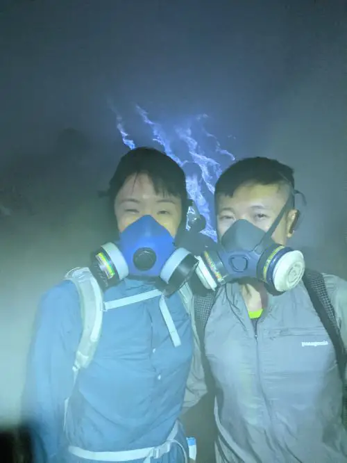 Jackie Szeto and Justin Huynh, Life Of Doing, wear gas mask while standing in front of Ijen's Blue Fire