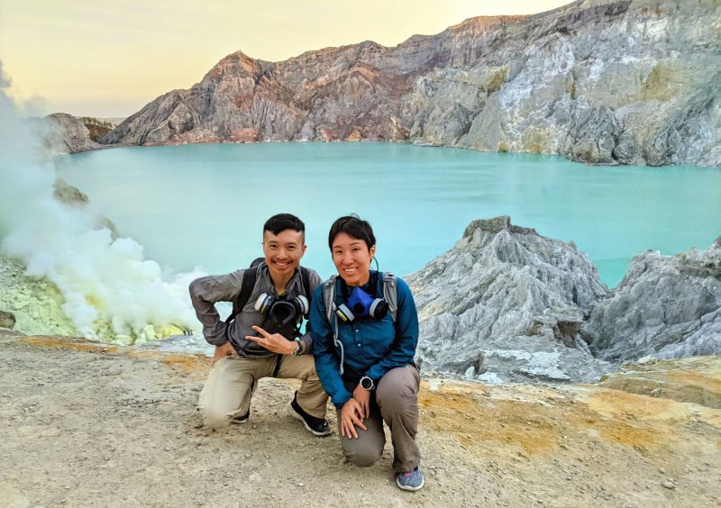 Justin Huynh and Jackie Szeto, Life Of Doing, stand in front of the turquoise lake at Ijen crater at sunrise