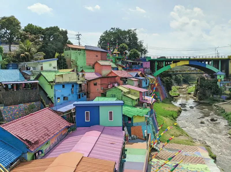 Pink, blue, green, and yellow houses and roofs with the colorful bridge overpass at Kampung Warna Warni Jodipan, Malang, Indonesia